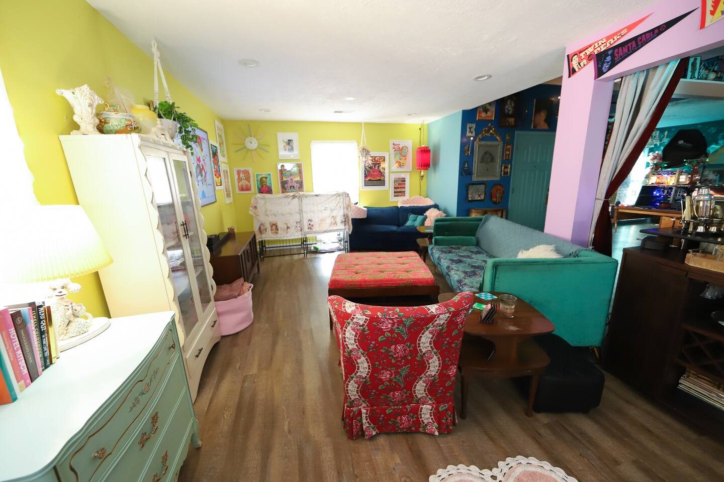Living room with yellow walls, blue couch, and a wall of framed art